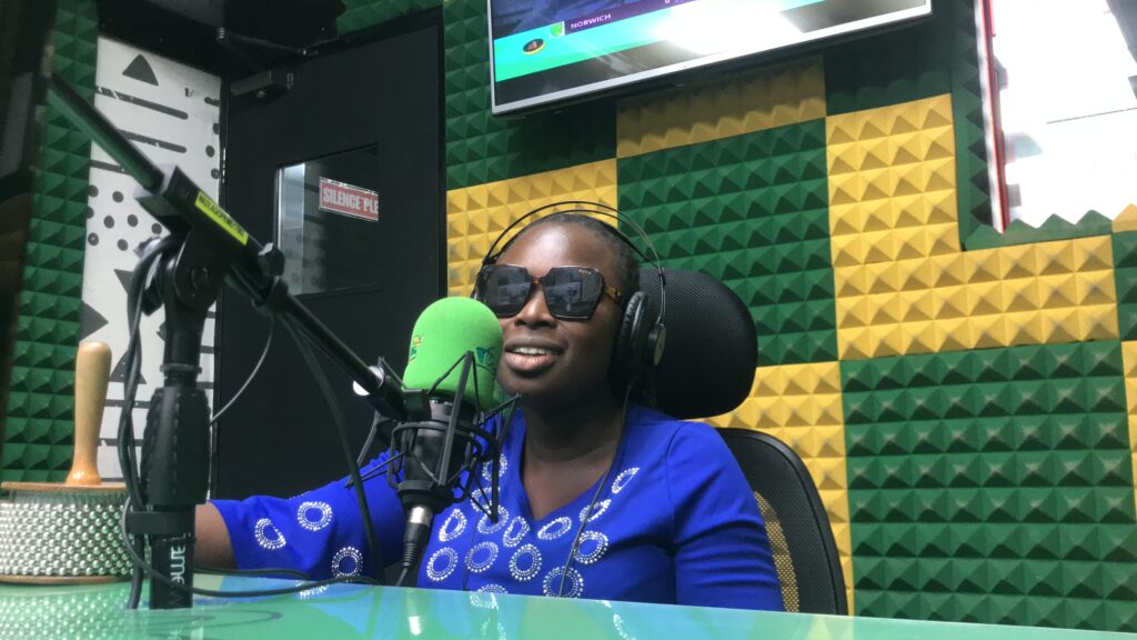 A blind lady hosting a live radio show with studio microphone before her